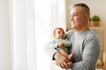 family, fatherhood and people concept - happy father holding with little baby son at home