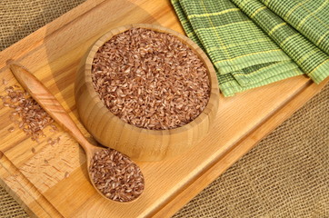 Uzbek devzira, the red rice for pilaf in a bamboo bowl and a wooden spoon on the Board