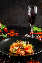 The concept of Spanish cuisine. Spanish salad with chorizo sausage, orange, tomato, baguette, tarragon, olive oil. A glass of cool wine on the table. background image. copy space