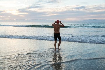 Fototapeta na wymiar Senior man preparing to swim in the sea at dawn