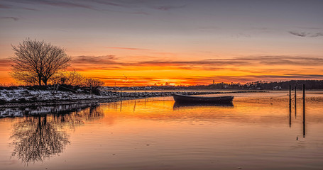 Fototapeta na wymiar A rowing boat in the sunset, tied to a pole in the water