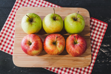 group of apples on wooden cutting board with napkin, close-up shot of organic products and healthy fruit