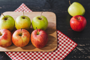 group of apples on wooden cutting board with napkin, close-up shot of organic products and healthy fruit