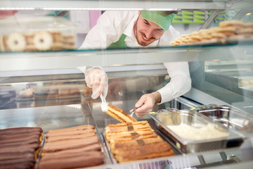 Bakery worker taking out biscuit cake from showcase