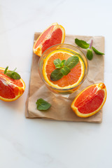 glass of drink with orange and mint leaves and orange slices top view on a white background.