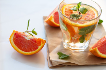 glass of drink with orange and mint leaves close up on a white background.