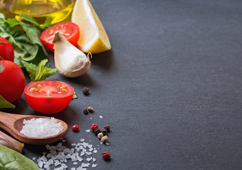 Basil, olive oil, salt and other ingredients on the black stone background