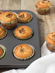 Homemade banana chocolate muffins in a baking form on a wooden background