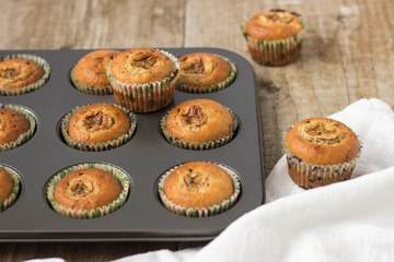 Homemade banana chocolate muffins in a baking form on a wooden background