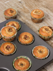 Homemade banana chocolate muffins in a baking form on a wooden background