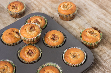Homemade banana chocolate muffins in a baking form on a wooden background