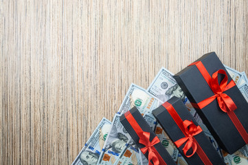 Three black gift box with a bow with dollars banknotes on a wooden table. top view, copy space