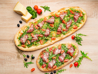 Pizza on Tabletop. Pizza wiht bacon, tomatoes, basil and arugula.