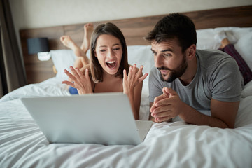Happy young man and woman is having fun in bed.