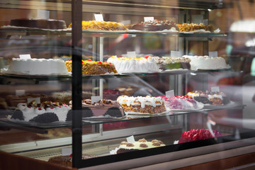 Appetizing cakes in the window of a pastry shop. Tasty sweets on the baking store shelves