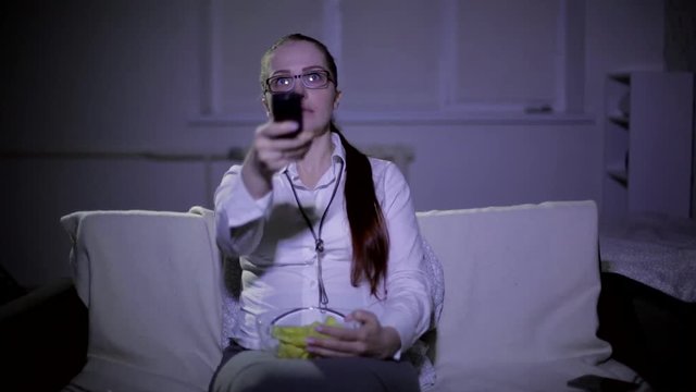 Lifestyle Woman Watching TV At Night On The Sofa And Eating Chips
