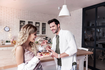 Dark-haired bearded man in a white shirt looking at his wife