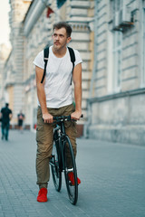 Obraz premium Portrait of young man walking with thoughtfully classic bicycle on city streets