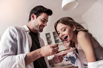 Dark-haired bearded man in a white shirt and his pretty wife feeling amazing