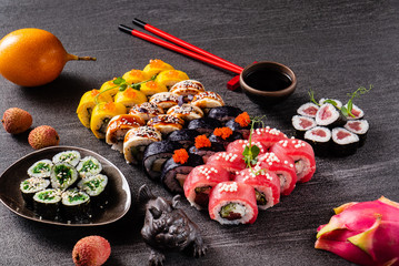 Sushi rolls set served on black stone slate on dark background