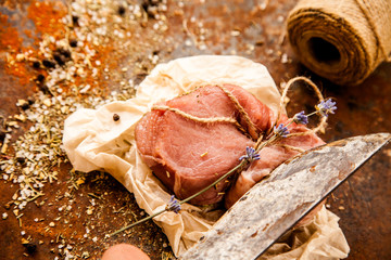 Raw fresh lamb meat and cleaver on dark background
