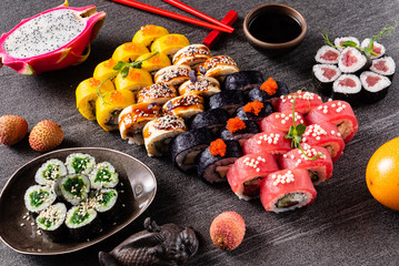 Sushi rolls set served on black stone slate on dark background