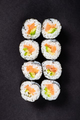 Sushi rolls set served on black stone slate on dark background