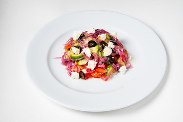 Fresh Greek salad in Plate with black olive,tomato,feta cheese, cucumber and onion isolated on white background.