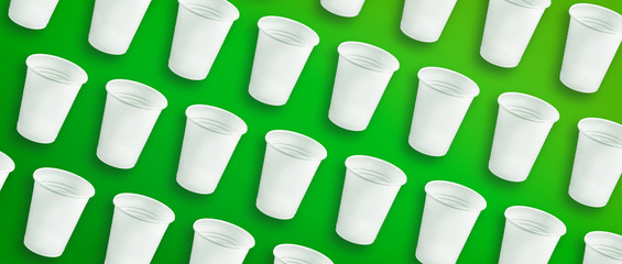 Single use white plastic cups on a green background
