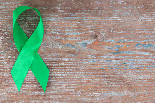 Green ribbon. Scoliosis, Mental health and other, awareness symbo on the wooden background with copy space