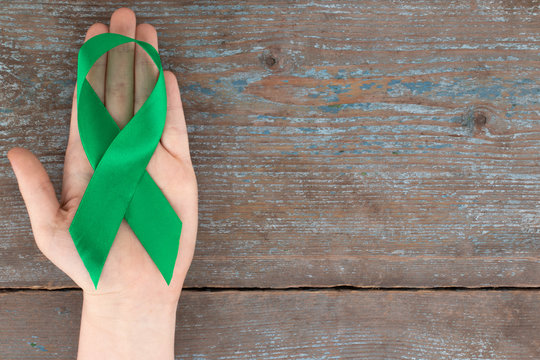 Green ribbon. Scoliosis, Mental health and other, awareness symbo on the wooden background with copy space