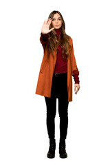 Full-length shot of Young woman with coat making stop gesture denying a situation that thinks wrong on isolated white background