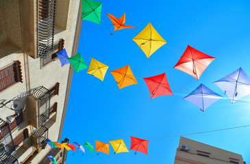 Fototapeta na wymiar Sciacca, Sicily: Colored umbrellas on the street in historical part of old city of Sciacca against blue sky .