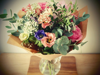 Romantic bouquet with roses, gypsophila and eucalyptus leaves. Modern arranged flowers in glass vase on wooden table