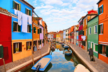 Fototapeta na wymiar Burano island picturesque street with small colored houses in row, windows, doors and water canal with fisherman boat. Venice Italy