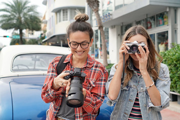 Young smiling photography students taking photos outdoors in urban setting