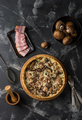 Mushroom Quiche Pie with champignons and cheese on dark background, top view. Savory tart with mushrooms. Galette. Tart with chicken. Chicken pie. Mushroom pie.