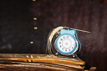 Old clock with ripe ears of wheat on a dark background