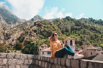 Fototapeta na wymiar Girl on the background of the high mountains of Montenegro. Style of life, travel. Old City of Kotor