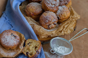 Cupcakes with raisins and candied fruits on a wooden background with a blue napkin and powdered sugar