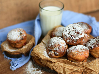 Cupcakes with raisins and candied fruits on a wooden background with a blue napkin and a glass of milk