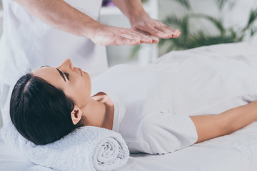 Fototapeta na wymiar young woman lying on massage table and receiving reiki treatment