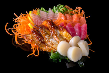 Obraz premium Set of Delicious Sashimi (raw sliced tuna, salmon, grouper, scallop, smoked eel, salmon) with carrot, cucumber, nori, lemon on black background. Traditional Japanese cuisine