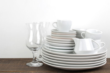 A stack of dishes. tableware on a brown wooden table. dishes for serving the table. plates and cutlery, cups and teapot, glasses.