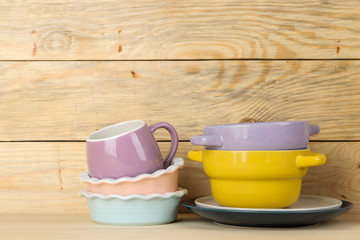 A stack of dishes. colored dishes on a natural wooden table. multi-colored cups and bowls.