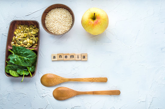 Spinach, pumpkin seeds, sesame, apple and two wooden spoons on a white background. Anemia concept. Close-up.