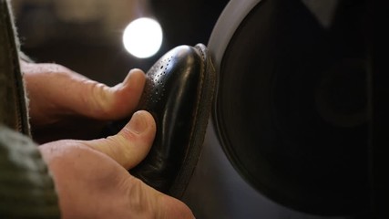 Sole of leather shoe being worn away on a grinding belt for repairing