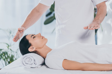 cropped shot of calm young woman receiving reiki treatment from male healer - obrazy, fototapety, plakaty
