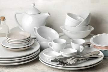 a lot of different dishes. Dinnerware. on a light concrete background. dishes for serving the table. various plates, bowls, and cups.