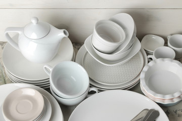 a lot of different dishes. Dinnerware. on a light concrete background. dishes for serving the table. various plates, bowls, and cups.